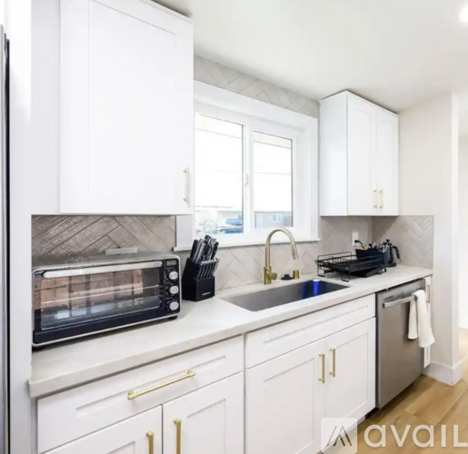 A kitchen with white cabinets and a black toaster oven.