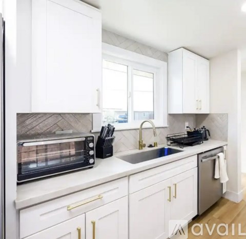 A kitchen with white cabinets and a black toaster oven.