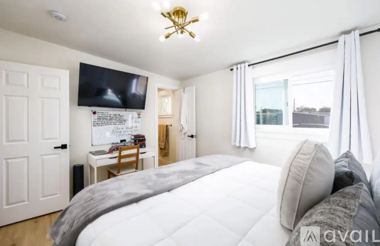 A bedroom with a large bed and a flat screen TV mounted on the wall.
