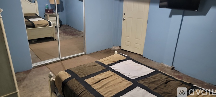 A bedroom with a bed, mirror, and a door.