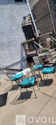 A patio with chairs and a table is in front of a building.