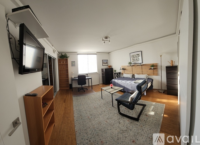 A bedroom with a bed, desk, and television.