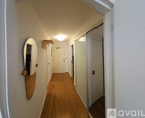A hallway with a mirror and wooden floors.