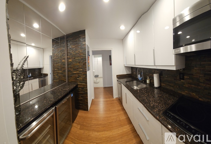A modern kitchen with wooden floors and a stone backsplash.