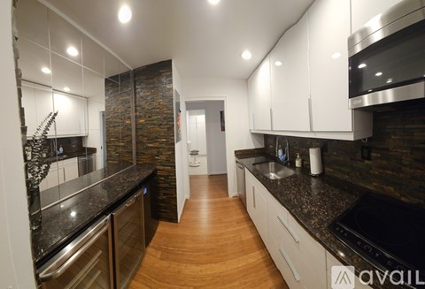 A modern kitchen with wooden floors and a stone backsplash.