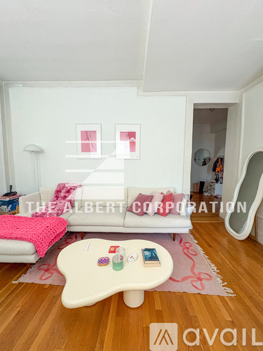A living room with a white couch and a pink rug.