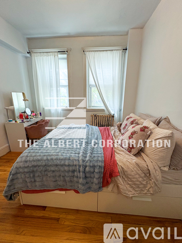 A bedroom with a bed covered in a blue and red blanket.