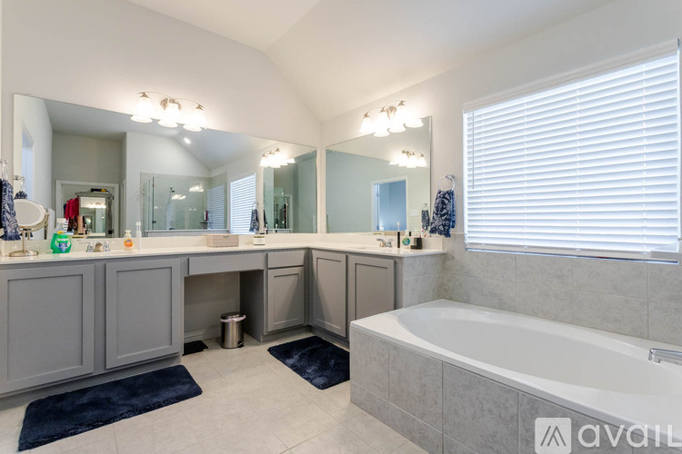 A large, well-lit bathroom with a bathtub, double sinks, and a large mirror.