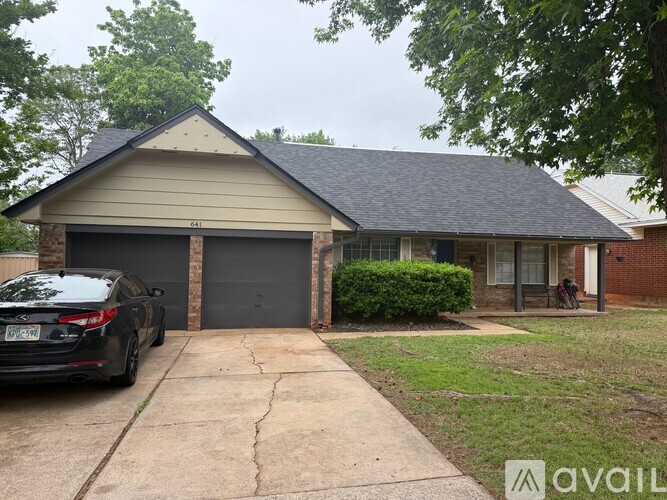 A black car is parked in front of a two-car garage.