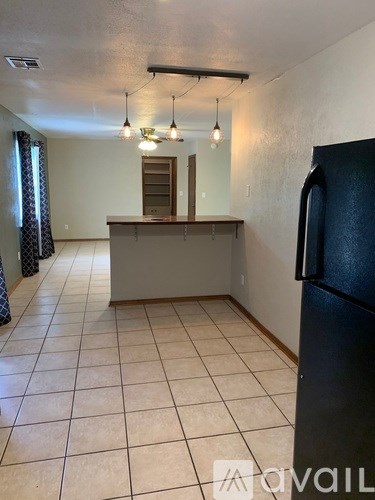 A kitchen area with a black refrigerator and a counter.