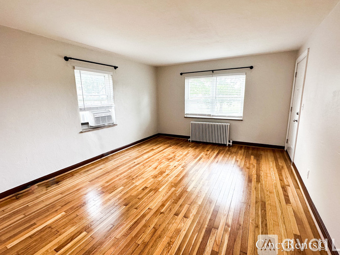 A room with wooden floors and a window with blinds.