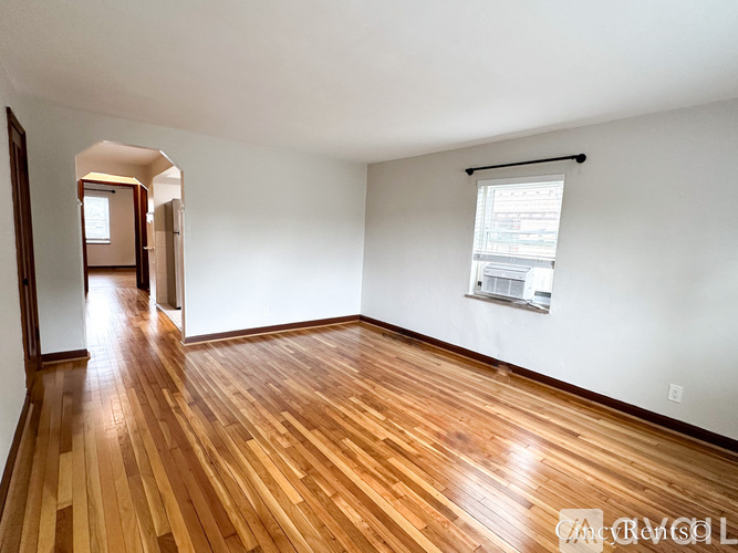 A room with wooden flooring and a window with blinds.