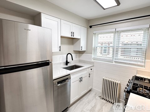 A kitchen with white cabinets and a stainless steel refrigerator.