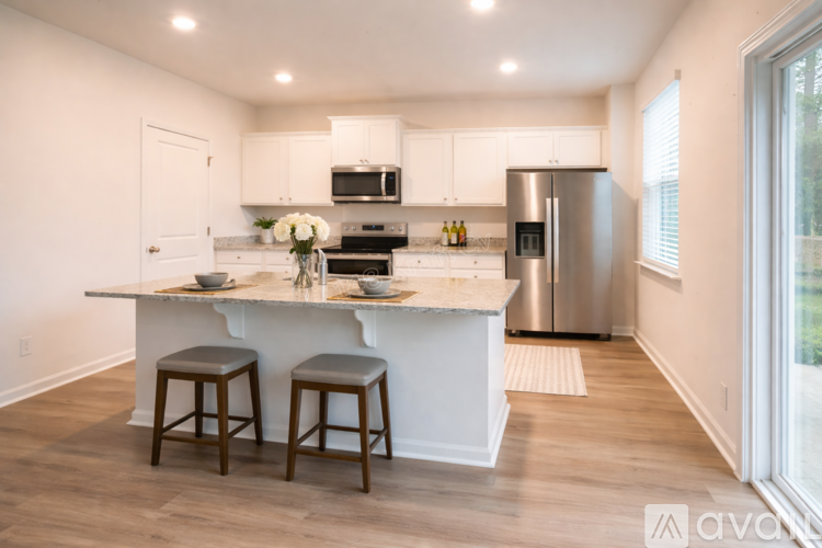 A kitchen with white cabinets and a marble island.