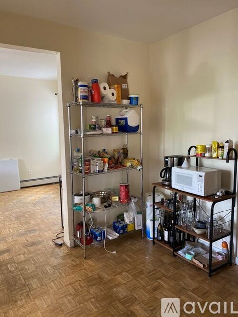 A kitchen pantry with a microwave on the shelf.