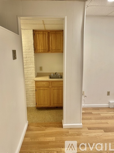 A kitchen area with wooden cabinets and a white brick wall.