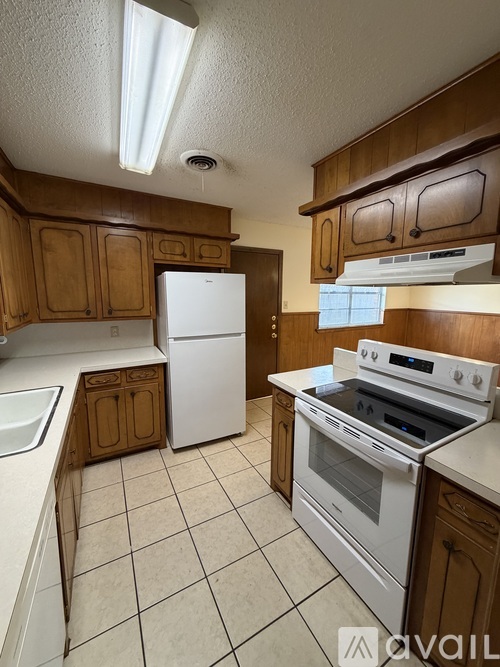 A kitchen with white appliances and wooden cabinets.