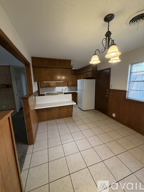 A kitchen with white tiles on the floor and wooden cabinets.