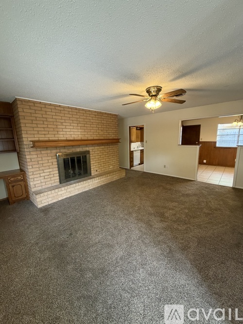 A living room with a fireplace and a ceiling fan.