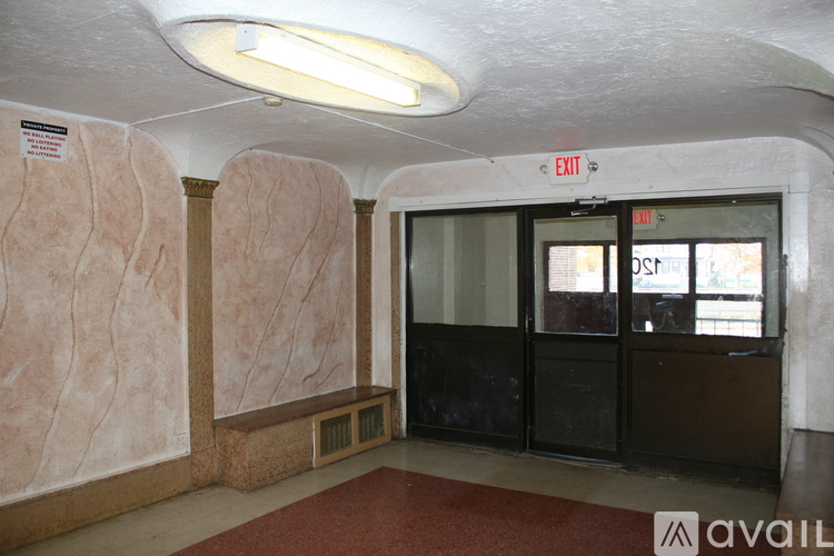 A hallway with a red carpet and a door with an exit sign above it.