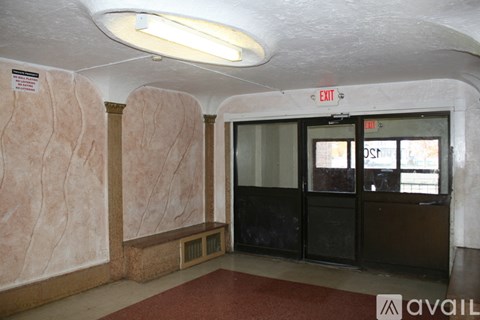 A hallway with a red carpet and a door with an exit sign above it.
