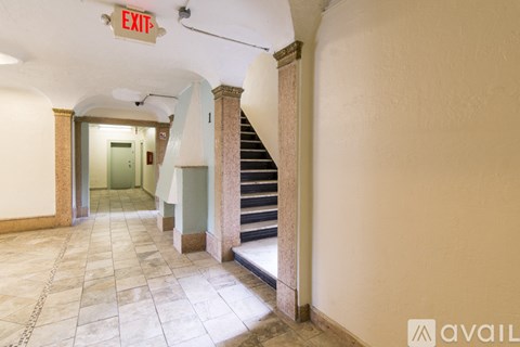A hallway with a staircase and an exit sign.