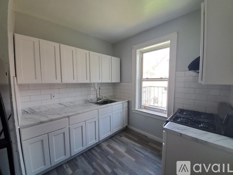 A kitchen with white cabinets and a marble countertop.
