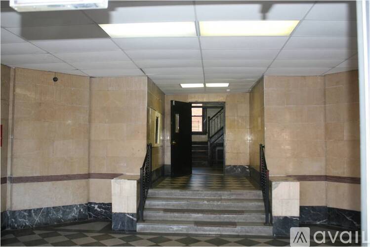 A hallway with a staircase and a marble floor.