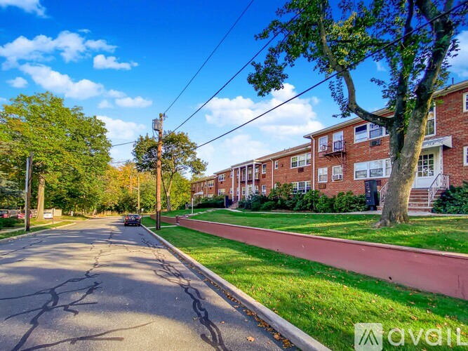 A tree-lined street with a brick building on the right.