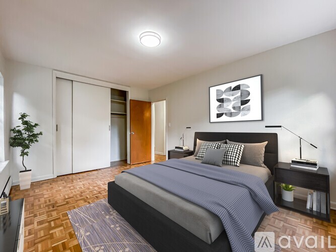 A bedroom with a bed, nightstand, and a plant.