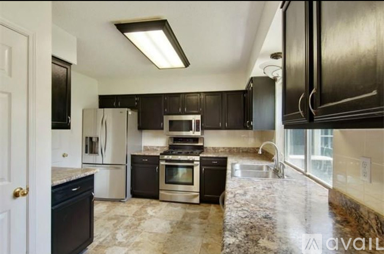 A kitchen with black cabinets and a marble countertop.