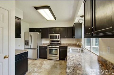 A kitchen with black cabinets and a marble countertop.