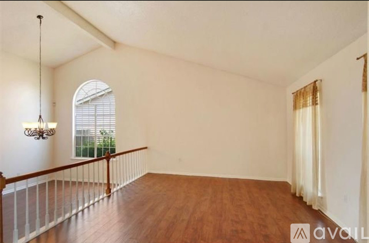 A room with wooden floors and a balcony with white railings.