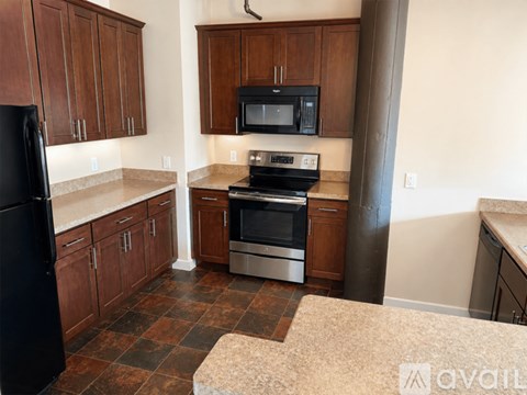 A kitchen with brown cabinets and a black refrigerator.