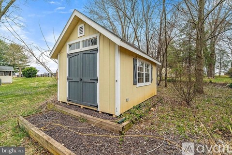 A small yellow shed with a black door and window.