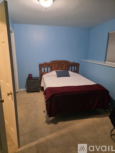 A bedroom with a bed, nightstand, and chair.