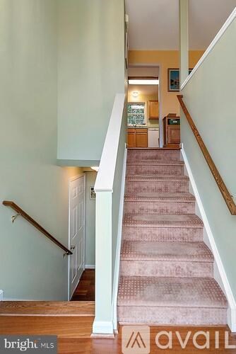A staircase with a pink carpet and wooden handrail.