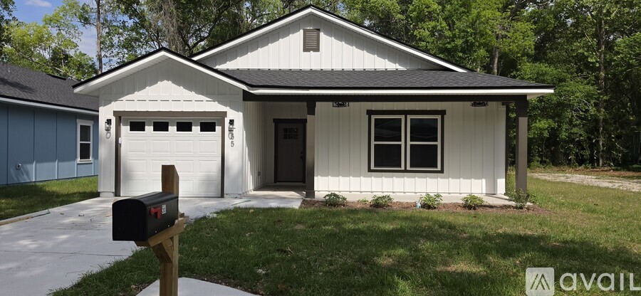 A white house with a black roof and a mailbox on the front porch.