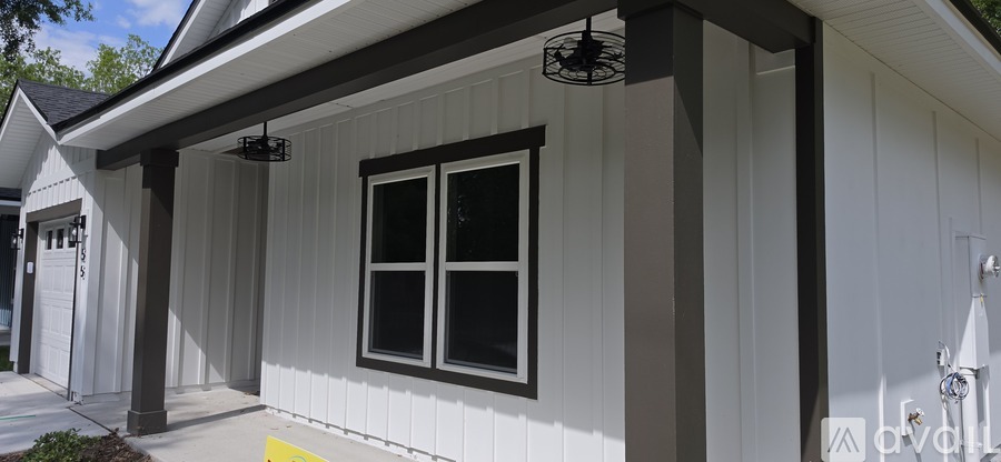 A white house with a black window and a black fan on the roof.