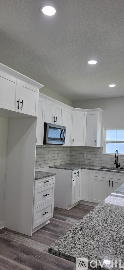 A kitchen with white cabinets and a granite countertop.
