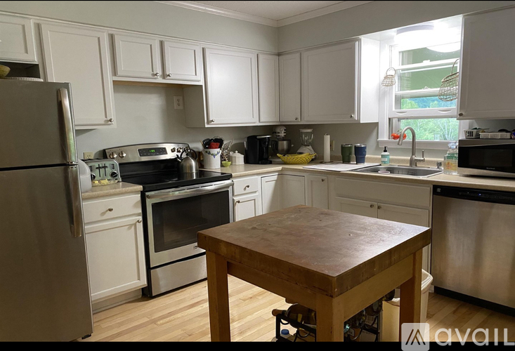 A kitchen with white cabinets and a wooden table.