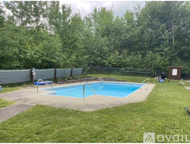A small pool surrounded by a fence and trees.