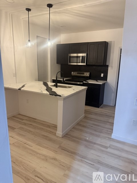 A kitchen with a white island and black cabinets.