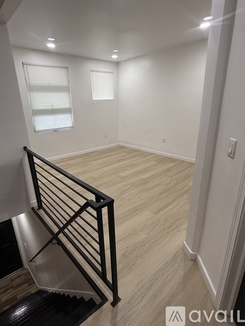 A room with wooden flooring and a staircase with a black railing.