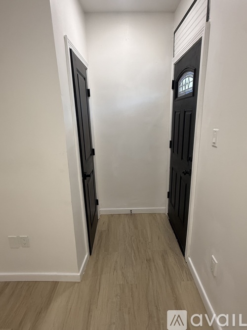 A hallway with a black door on the right and a white door on the left.