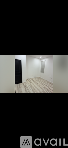 A room with wooden flooring and a black door.