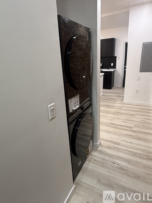 A modern kitchen with a dark wood floor and white walls.