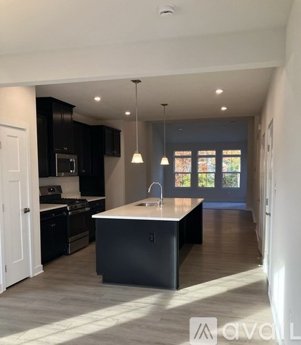 A kitchen with black cabinets and a white island.