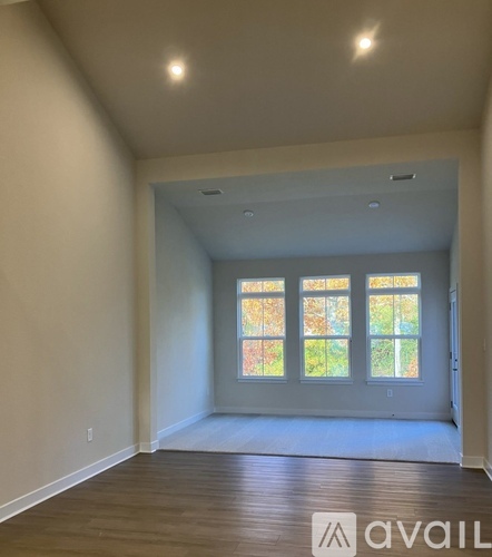 A spacious room with a large window and wooden flooring.