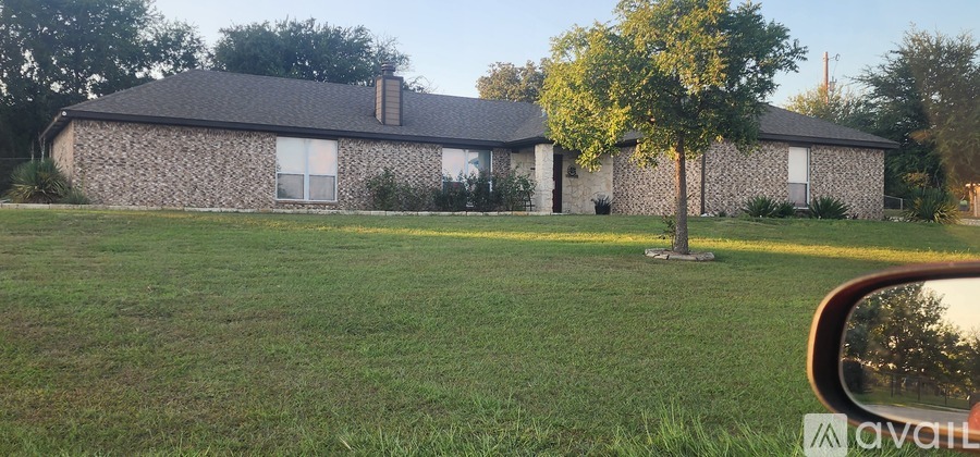 A house with a stone wall and a tree in front of it.